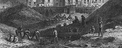 Deux monticules de scories séparés des bâtiments au fond par une palissade. Des personnages, dont quelques enfants, s'affairent, triant, remplissant des sacs et des paniers