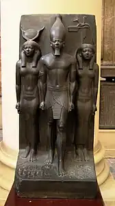 Triade du 17e&nbsp;nome, Cynopolis, nome du Chacal. Le personnage du nome passe son bras dans le dos du roi. 92,5&nbsp;×&nbsp;43&nbsp;cm. Musée du Caire JE 40679