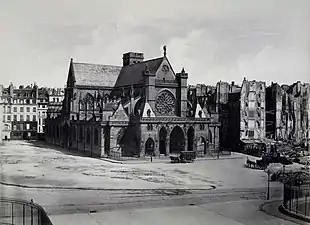 Vue de l'église Saint-Germain-l'Auxerrois en 1858 après l'agrandissement de la place du Louvre et avant la construction de la mairie du 1er&nbsp;arrondissement (photo d'Édouard Baldus) : longeant l'église, l'ancien cloître Saint-Germain-l'Auxerrois était situé dans l'espace libre autour de l'église.
