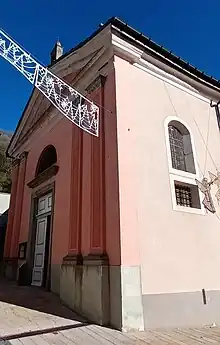 Photographie de l'église Saint-Maurice d'Orelle vue de face en rose, avec cinq fenêtres au sud et de grandes portes blanches.