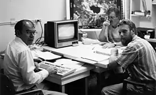 À gauche, René Verreault, physicien, au centre Gilles-H Lemieux, géographe, tous deux chercheurs et professeurs émérites à l'Université du Québec à Chicoutimi s'entretenant avec Alain Laroche (Interaction Qui) sur les résultats de la télédétection par le satellite Landsat d'un site expérimental (Événement Ouananiche, 1990).