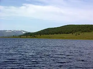 le lac avec une forêt et la chaîne d'Aigoulak au fond.