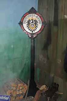 Photo d'un poteau surmonté de l'aigle noir allemand et de la mention Deutsches Reich, c'est-à-dire Empire allemand.