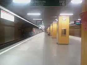 Le quai central avec une rangée centrale de colonnes de soutènements et à gauche l'arrivée d'une rame