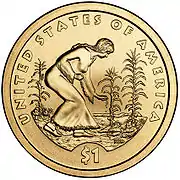 Pièce de monnaie représentant une femme plantant des graines dans un champ peuplé de maïs, de haricots et de courges. En plus les inscriptions UNITED STATES OF AMERICA, NEN et $1.