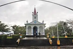 La façade de la chapelle, de probablement huit mètres de large, posée dans un petit parc surélevé de sept marches.