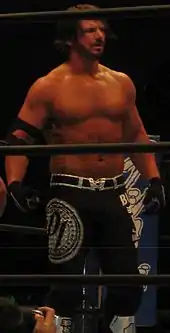 Catcheur en pantalon noir regardant à sa gauche.