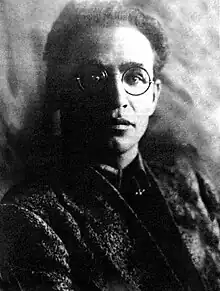 Photographie de face en noir et blanc d'un homme à lunette.