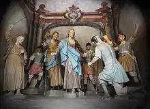 Photographie en couleurs. Groupe de statues colorées représentant les soldats en train de capturer Jésus. Le soldat au premier plan, de dos, à l'oreille coupée.