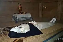 Reconstitution de la tombe d'une femme avec de nombreux éléments de mobilier à ses côtés dans un musée.