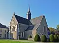 Photographie d'une abbaye surmontée d'un clocher terminé par une flèche.