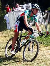 Homme sur un VTT portant un maillot et un cuissard multicolores.