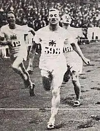 Photo d'un homme passant une ligne d'arrivée, à ses côtés ses concurrents.