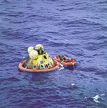 Photographie en couleur de la capsule d'Apollo 11 flottant en mer lors de la récupération des astronautes.