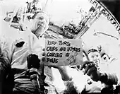 Deux hommes tiennent une feuille avec des inscriptions.