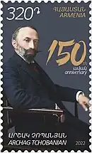 Timbre en couleur représentant, assis, un homme barbu portant un costume et une cravate.