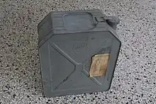 Photographie d'un jerrican en métal gris, censé contenir du pétrole