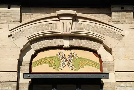 Linteau en fer, sgraffite et double arc surbaissésurmontant la baie gauche du premier étage.