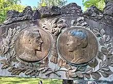 deux effigies en médaillons entourés de branches de laurier représentant à gauche un visage masculin regardant vers la droite un visage féminin.