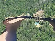 Méandre d'une rivière avec un bâtiment au toit vert au centre de ce dernier