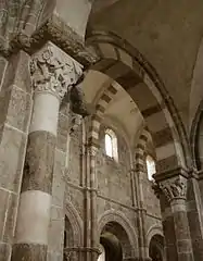 Les parties hautes de la nef vues depuis le collatéral sud : au premier plan, la 5e&nbsp;pile côté sud dont le chapiteau représente David et le lion, en arrière-plan, les fenêtres hautes du côté nord de la nef surmontant les arcades donnant sur le collatéral nord.