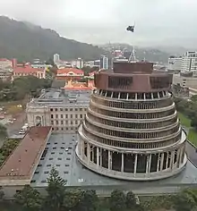 Photographie aérienne montrant un bâtiment tronconique moderne posé sur une base plus vaste de forme rectangulaire.