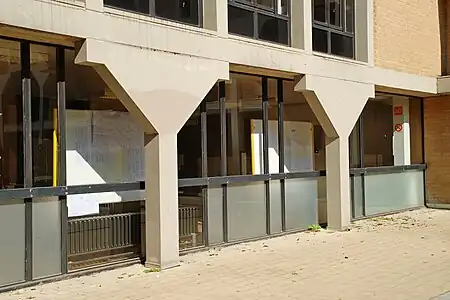 Colonnes de béton blanc soutenant la galerie.