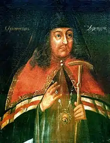 Peinture représentant un évêque orthodoxe russe habillé pour une cérémonie ; il porte un médaillon représentant la Vierge et son enfant, ainsi qu’un sceptre dans sa main.