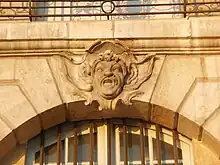 Photographie rapprochée d'un visage gravé dans un mur jauneatre.