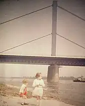 Photographie couleur ancienne d'un pont à haubans vu de la rive.