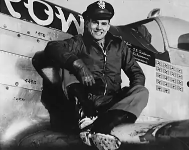 Le capitaine Clarence E. Jr. « Bud » Anderson, as du 357th Fighter Group, est assis sur l’aile de son P-51 Mustang (B6-S, numéro de série 44-14450) surnommé « Old Crow ».