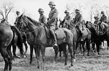 Photo noir et blanc montrant un groupe d'hommes en uniforme et à cheval.