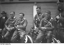 Photo de quatre hommes en tenue de pilote moto, assis sur leurs deux-roues.