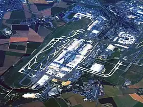 Vue aérienne de l'aéroport en juillet 2010 :• au premier plan, Le Mesnil-Amelot ;• à droite, 1re aérogare (circulaire) ;• au centre, 2e aérogare et ses terminaux.