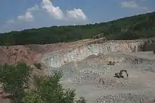 Vue du front de taille de la carrière de Moissey montrant, à gauche les conglomérats du Permien et le plan de discordance les séparant du filon d'eurite