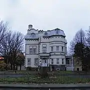 La façade d'un bâtiment de trois étages, de plan complexe, revêtue de briques de couleur beige.