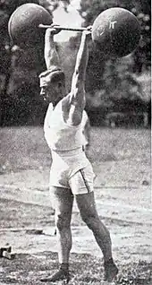 Photo d'un homme tenant des deux mais, bras tendus un haltère.