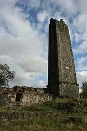 Vue d'une cheminée d'usine en ruines sur le domaine de Villèle.
