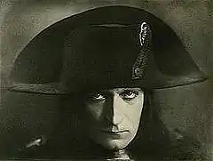 Photographie en noir et blanc de la tête d'un homme coiffé du chapeau caractéristique de Napoléon premier.