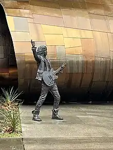 Photographie d'une statue d'un homme debout tenant une guitare.