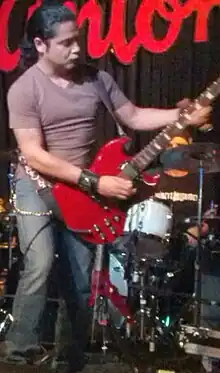 Un homme, debout, jouant de la guitare basse.