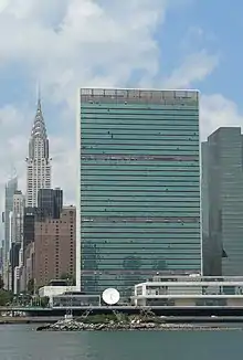 Photo représentant U Thant Island, avec le Chrysler Building et le siège des Nations unis en arrière plan. L'île est peu visible  du fait de sa taille modeste.