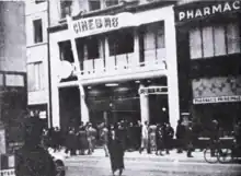 Photo noir et blanc de la façade avec une enseigne Cinébref en grandes lettres capitales et de nombreux piétons sur le trottoir devant le cinéma