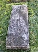 Seul vestige de l'ancien cimetière, une croix  sculptée sur une pierre tombale à droite de l'église.