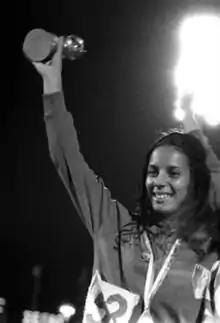 Une athlète en tenue de sport, brandissant un trophée.