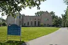 photo d'un grand bâtiment à deux ailes, entouré de verdure