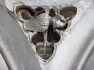 Photographie en couleurs d'une sculpture représentant un animal fabuleux posé sur la tête d'un enfant.