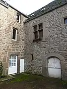 Une fenêtre à meneau et l'entrée cochère murée, même habitation.