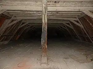 Photographie d'un combles à la charpente en bois.