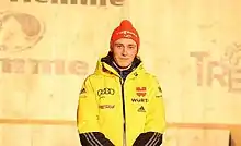 Photographie d'un homme debout en plan américain, habillé en jaune.